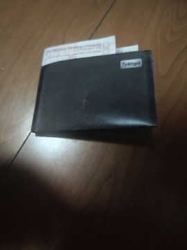 The image features a black wallet laying flat on its side, with a piece of paper attached to it. The wallet has a label that reads "SBIG" on it. The background of the image appears to be a wooden surface or table. There is also some text in the image, which seems to be related to the wallet and the post.