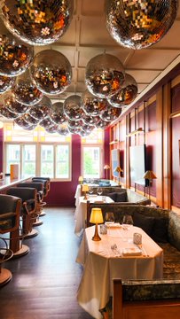 This image shows a stylish dining area at Mandala Club, Singapore, with a bar and tables set for a dinner, likely setting the scene for the "founder & investor dinner" mentioned in the post. The disco balls overhead add a festive atmosphere to the elegant setting.