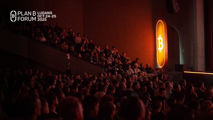 Promotional image for the 'PLAN B FORUM LUGANO OCT. 24-25 2025,' showing an audience seated in a dimly lit auditorium with a glowing Bitcoin logo on the wall.