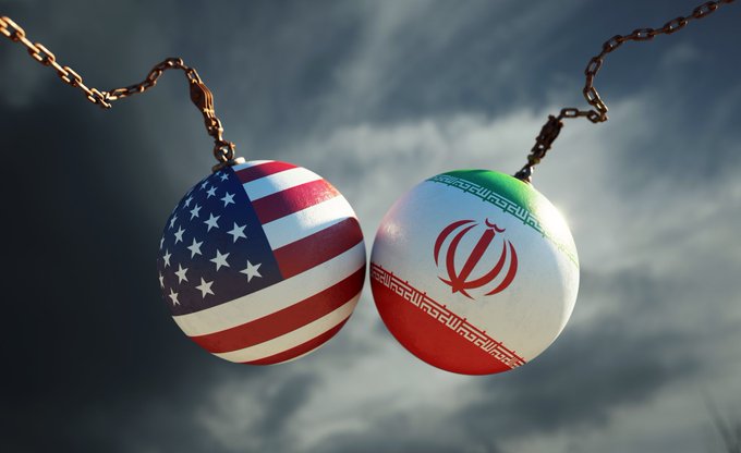 Two wrecking balls painted with the U.S. and Iranian flags hang on chains against a stormy sky, symbolizing the fragile and potentially explosive truce between the two nations. The imagery visually reinforces the post's warning that renewed U.S.-Iran tensions could disrupt global shipping routes and fuel inflation, putting pressure on assets like Bitcoin and the S&P 500.