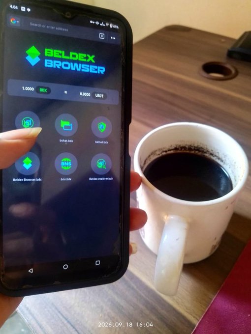 A hand holds a smartphone displaying the 'BELDEX BROWSER' app interface with options for Beldex Browser Beta, belnet beta, belnet app, box beta, and Beldex explorer beta, while a white mug filled with dark coffee sits on a wooden table beside it; the timestamp reads 2026.09.18 16:04.