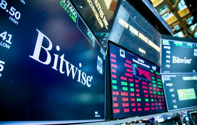 Close-up of stock market monitors at the New York Stock Exchange displaying financial data and the Bitwise logo prominently.