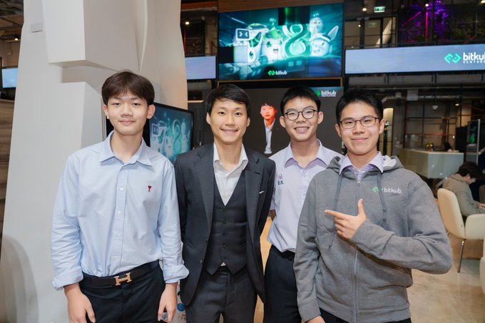 Four men pose for a photo at a Bitkub event, with company logos visible in the background.