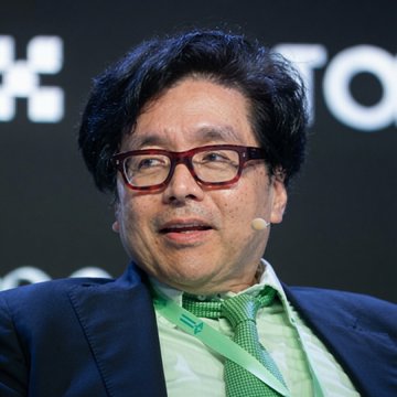 The image shows Tom Lee, co-founder of Fundstrat and chairman of Bitmine ($BMNR), speaking at a conference while wearing a green tie and glasses. His appearance relates directly to the post as he leads Bitmine, which recently made its smallest weekly $ETH purchase on record, acquiring 7,430 ETH ($13.92 million) to bring holdings to 5,777,468 ETH.