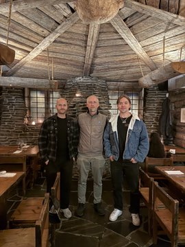 Three men stand together smiling inside a rustic wooden sauna or lodge with exposed beam ceilings and stone flooring, appearing to pose for a photo during the poster's visit to Helsinki and the BTCHEL event. The caption complements the post by visually capturing the "European Bitcoin vibe" and networking experience the author described, likely featuring one of the friends or contacts—such as Sakari Puisu—mentioned in the message.