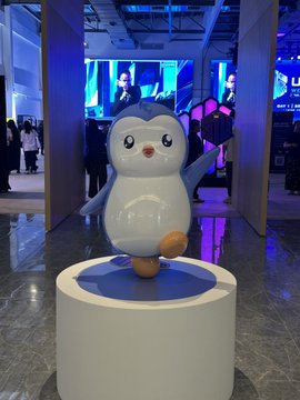 A large inflatable Pudgy Penguin mascot stands on a circular pedestal at the Ultra Web3 Fest, representing the Pudgy Penguins pop-up booth showcase. The mascot's pose and the event setting align with the post's mention of featuring official Pudgy Penguins toys and merchandise at the convention.
