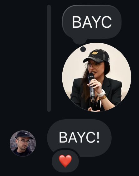 The image features a person wearing a black hat, holding a microphone, and talking into it. The caption of the image reads "This is crazy @mfigge is EVERYWHERE I believe in something. And it’s called BAYC!".