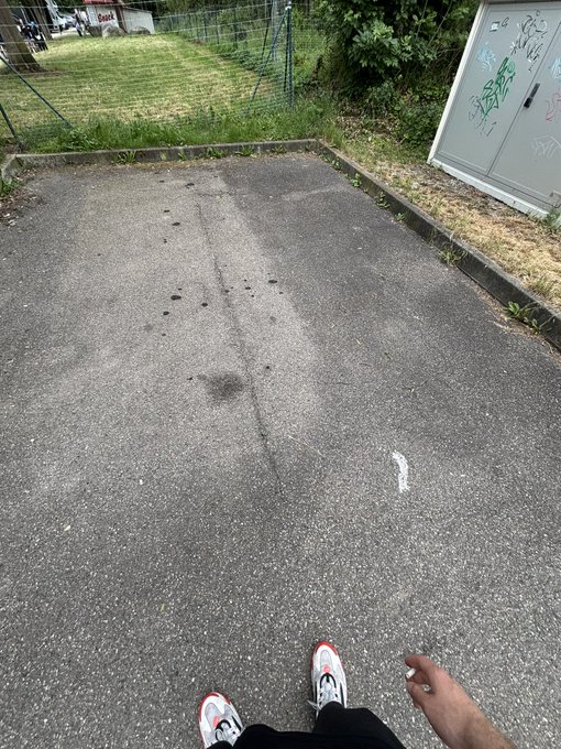 The image shows a person's feet wearing white sneakers, standing on an asphalt road with a fence nearby. There are also two cars parked behind them. The caption of the image reads "$neet adventure begins Imma keep you guys updated Should be gas". This suggests that the person is about to embark on an outdoor activity or journey and has been informed by someone else to stay connected during their adventure.

The person's feet are positioned in front of a fence, indicating they might be at the beginning or end of a path or trail. The presence of cars parked behind them further supports this notion that they have arrived at or left from a location where vehicles were parked.