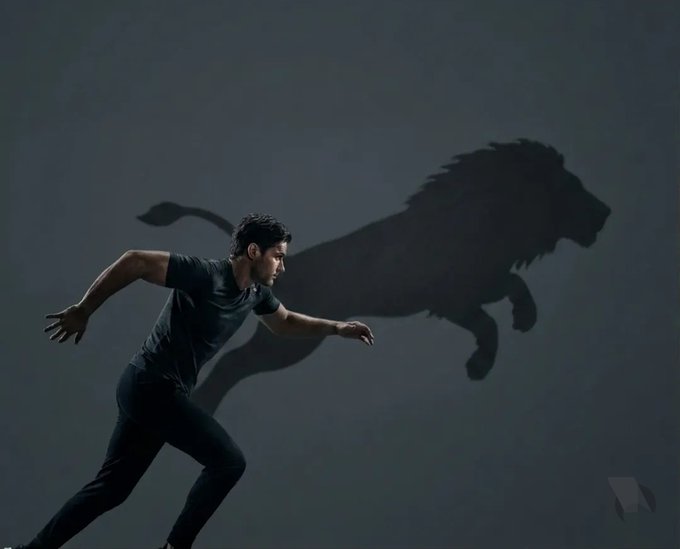 A man in black athletic wear is shown mid-stride against a dark background, with a large shadow of a leaping lion projected behind him.