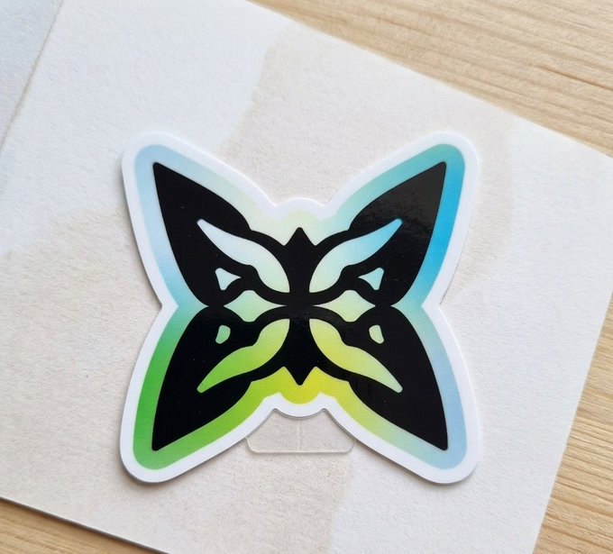 The image features a sticker with a butterfly design, which has been cut out from a piece of paper. The butterfly is colored green, black, and yellow, giving it an artistic appearance. The sticker is placed on top of a white surface, possibly a table or a card. The text in the image reads: "Happy Weekend After spending more time exploring @quipnetwork", which suggests that someone has been working on a project related to Quip network. The post also mentions that there are many complex systems and infrastructure projects being discussed, which might be difficult for some people to understand due to their abstract nature.