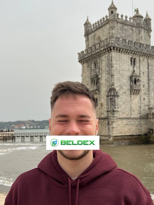 A young man in a maroon hoodie stands with eyes closed in front of the Belém Tower, with a 'BELDEX' logo overlaid across his face.