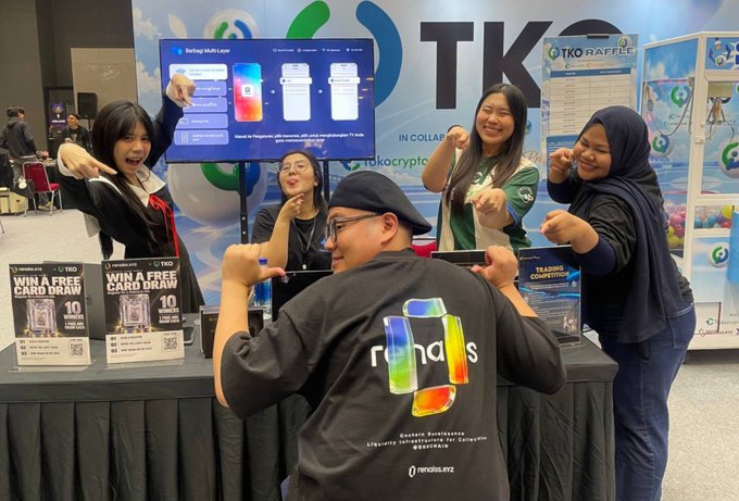 A group of five enthusiastic people pose with thumbs up and peace signs at a trade booth featuring "rhaas" branded merchandise, with visible signage for a "Win A Free Card Draw" promotion and "TKO" branding, capturing the lively atmosphere of the Indonesia Card Party event alongside Renaissance Club and Tokotoken.