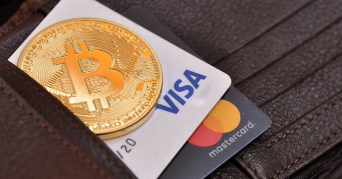 A brown wallet with a Visa credit card inside has been photographed, with a Bitcoin coin placed next to the card, suggesting the wallet owner may be interested in cryptocurrency or trading. The post highlights that Mastercard is acquiring a Bitcoin company worth up to $500 million and reports that this company is worth at least $1.8 billion, indicating an emerging trend in digital currency transactions.