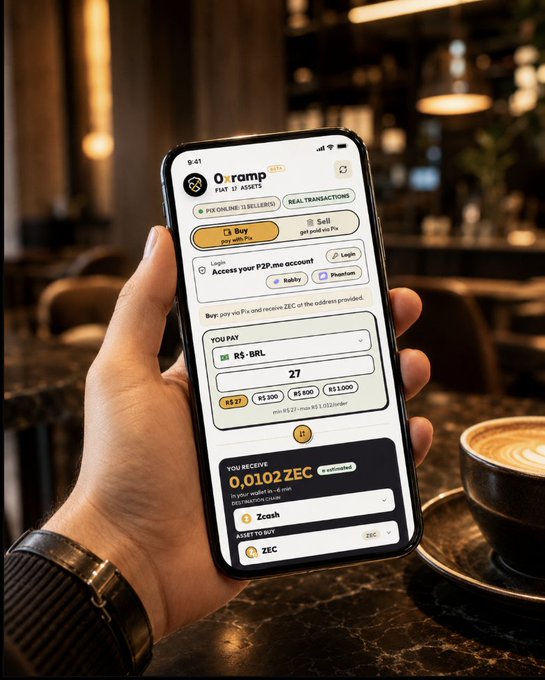 A hand holds a smartphone displaying a crypto payment app called '0x.ramp' in a cafe, showing a transaction converting R$27 to 0.0102 ZEC (Zcash).