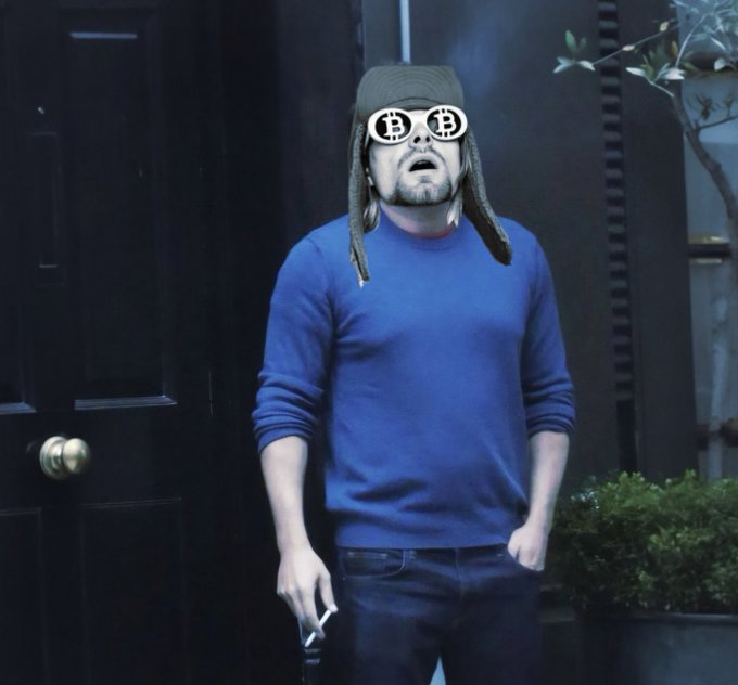 A man wearing a blue sweater, black jeans, and a trapper hat stands outside a door, with a Bitcoin logo digitally overlaid on his glasses.