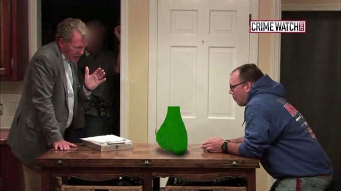A still from a Crime Watch Daily show showing a confrontation between a man in a suit and another man in a blue hoodie across a table with a green vase.