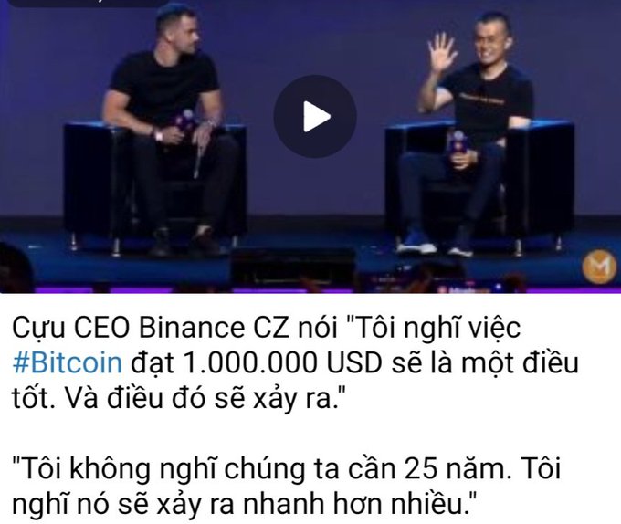 Two men sit on stage in black chairs; Vietnamese text below reads about former Binance CEO CZ discussing Bitcoin reaching 1,000,000 USD.