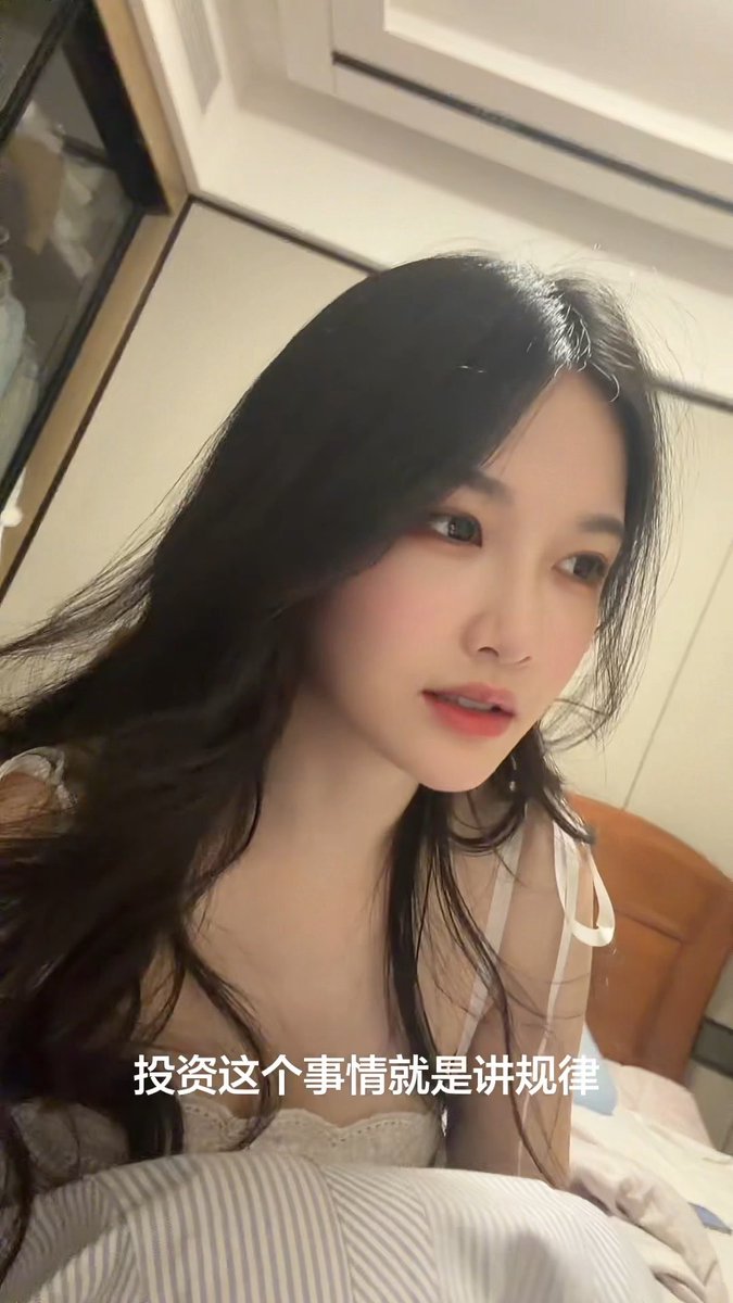 A young woman with long dark hair wearing a light-colored top, with Chinese subtitle '投资这个事情就是讲规律' (Investing is about following patterns).