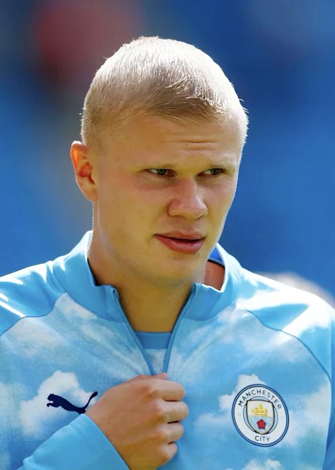 A young blonde Manchester City player, wearing the club's sky-blue Puma training jacket with the Manchester City crest visible on the chest, looks focused and serious—capturing the tense atmosphere as bettors wager $188k against City winning their match against Sunderland, potentially yielding $652,411 on Polymarket.