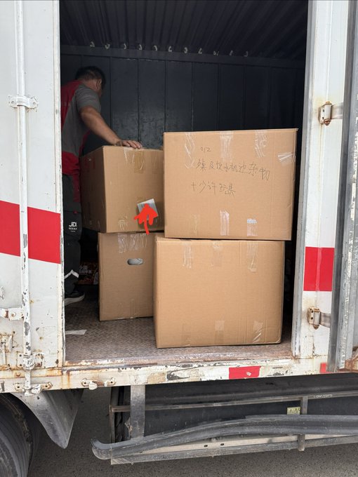 A worker is loading cardboard boxes into the back of a truck, with the largest box displaying Chinese text that reads "事关反垄断及经营者集中审查" (related to antitrust and business concentration review) along with numbers like "1520" and "1200." This image illustrates the post's theme of clearing out over a dozen boxes through manual labor, with the anticompetitive review reference symbolically tying into the achievement of the 85,000 price target mentioned.