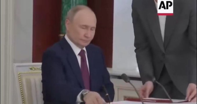 The image shows Russian President Vladimir Putin seated at a desk, appearing to sign a document, with another person standing beside him, in what appears to be an official setting. The AP logo is visible in the corner, and the image directly relates to the post by depicting Putin's signing of Russia's crypto market structure bill into law.