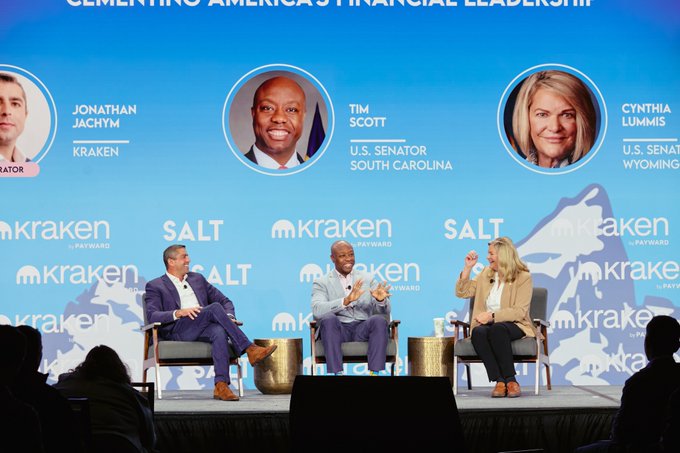 At the Wyoming Blockchain Symposium, a panel discussion featuring Jonathan Jachym of Kraken/Payward, U.S. Senator Tim Scott (South Carolina), and U.S. Senator Cynthia Lummis (Wyoming) takes place on stage, with a backdrop displaying their headshots alongside the "Kraken by Payward" and "SALT" logos under the banner "ELEMENTING AMERICA'S FINANCIAL LEADERSHIP."