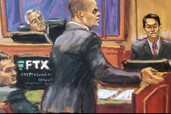 A courtroom sketch depicts a man in a suit standing before the bench during the FTX Cryptocurrency Derivatives trial, with the FTX logo visible on a display.