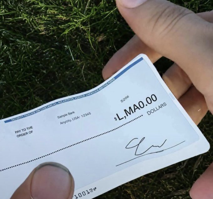 A hand holds a novelty check made out to '$LMAO.00' from 'Sample Bank' in Anycity, USA.