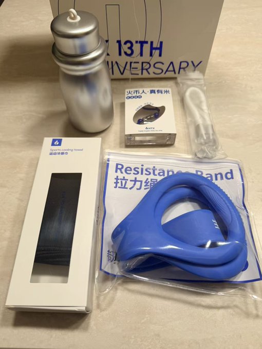A 13th anniversary promotional package from Decathlon containing a metal water bottle, a sports cooling towel, a blue resistance band, an exercise mouth tape, and other fitness accessories.