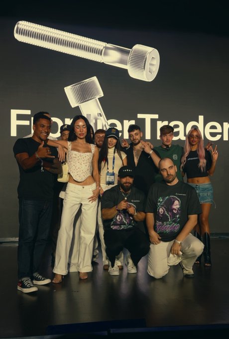 A diverse team celebrates together on stage in front of a large illuminated "Frontier Traders" sign, with one member wearing a "Solana" shirt, capturing the energetic, esports-like atmosphere of the successful tournament.