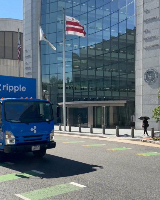 A blue Ripple truck is parked in front of the U.S. Securities and Exchange Commission building, referencing a playful jab at Gary Gensler and a statement that XRP is here to stay.