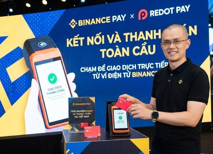 Changpeng Zhao, the former CEO of Binance, poses with a Binance Pay and RedotPay card during a collaboration event in Vietnam, highlighting the global partnership between the two payment services—now at the center of a $500 million lawsuit.