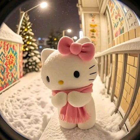 A Hello Kitty figurine wearing a pink bow and scarf, posed in a snowy diorama with a decorated Christmas tree and colorful tiled wall, viewed through a fisheye lens.