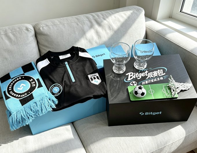 The image features a couch with two boxes sitting on top of it, one containing sports memorabilia such as soccer balls and other items related to sports. The other box contains wine glasses and a shirt. A glass of wine can be seen next to the sports memorabilia box, suggesting that someone might have been enjoying a drink while admiring their collection or watching a game.