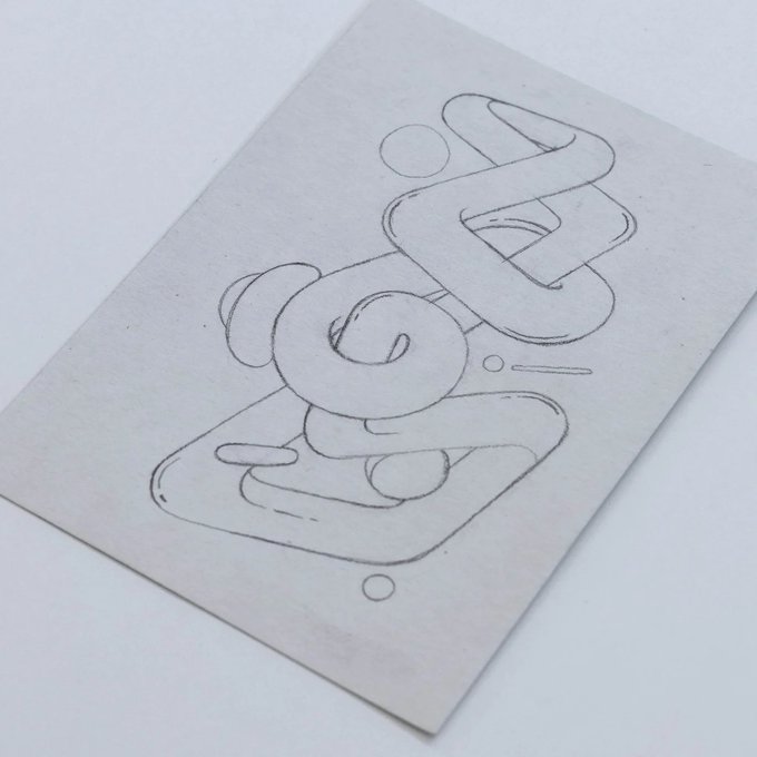 A piece of beige paper on a white surface featuring an abstract black line drawing composed of loops, curves, and geometric shapes.