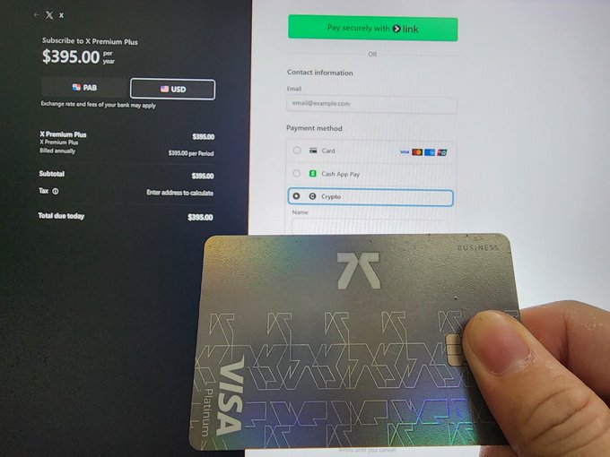 The image shows a person holding up a Visa credit card with a green stripe on it against a white background, possibly a computer screen or a piece of paper. The text displayed on the screen indicates that the card can be used for payments worldwide, regardless of the currency being used. This means that the card is accepted in various countries and can be used to make purchases without needing to exchange money. The image also includes a link to a post about the card's features, which suggests that it might be an advertisement or promotional material related to the Visa credit card.