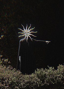 A surreal figure in a black cloak with a golden sunburst for a head points outward from behind a bush in a dark, dreamlike setting.