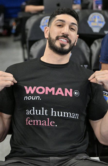The caption for this image could read: "A man proudly displays a black t-shirt with a declaration of gender expression, sparking conversation about language and identity." This caption succinctly describes the key text on the t-shirt and hints at the controversy suggested by the accompanying post, relating the image to the discussion about gender norms and definitions.