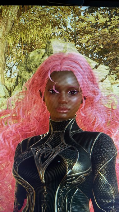 A 3D-rendered or digital art image of a dark-skinned woman with long, flowing bright pink hair, wearing an intricate black and gold armor-like bodysuit, posed against a lush green forest background.