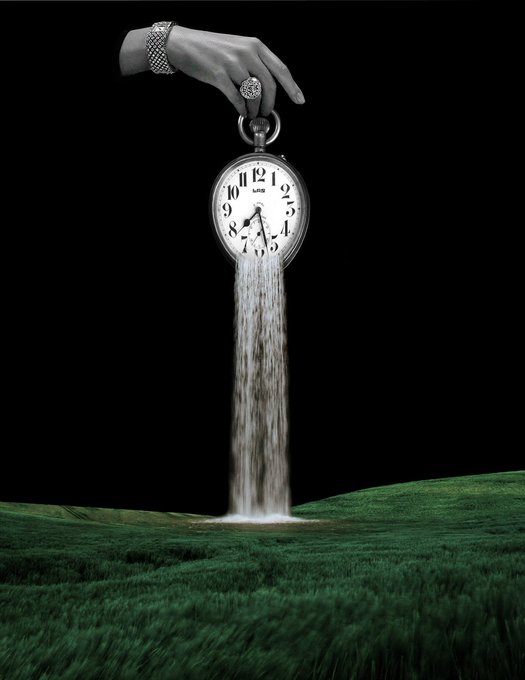 A surreal black-and-white image showing a hand holding a pocket watch from which sand pours like a waterfall onto a green grassy field below.