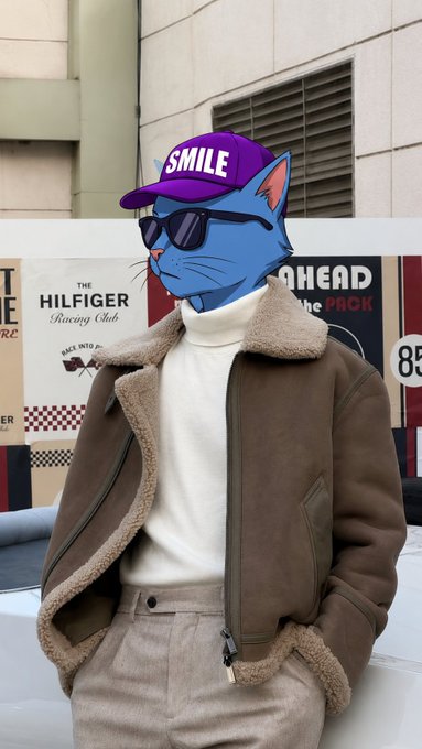 A person wearing a brown shearling jacket, white turtleneck, beige pants, sunglasses, and a purple 'SMILE' cap with a blue cat face filter applied.