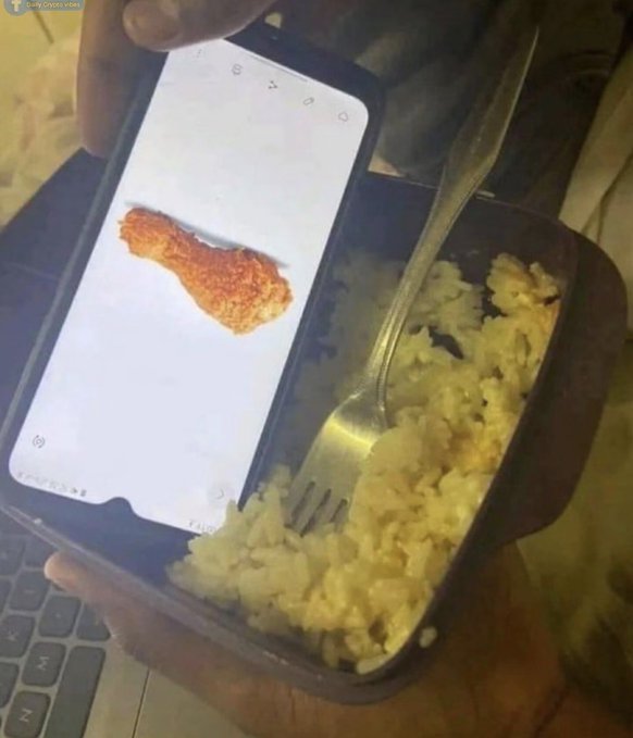 A person holds a smartphone displaying a reference image of a breaded chicken tender next to a wooden bowl of rice and scrambled eggs with a fork.