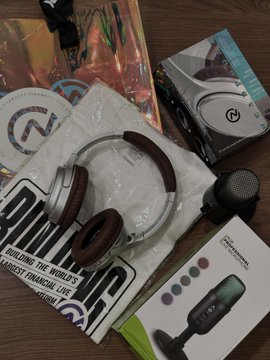 A collection of new streamer gear is laid out on a wooden surface, including a white "Elgato" branded box, a microphone in packaging labeled "Professional Condenser," a branded "Civic" shirt or tote, and packaged headphones, likely unboxed from the dinner giveaway mentioned in the post.