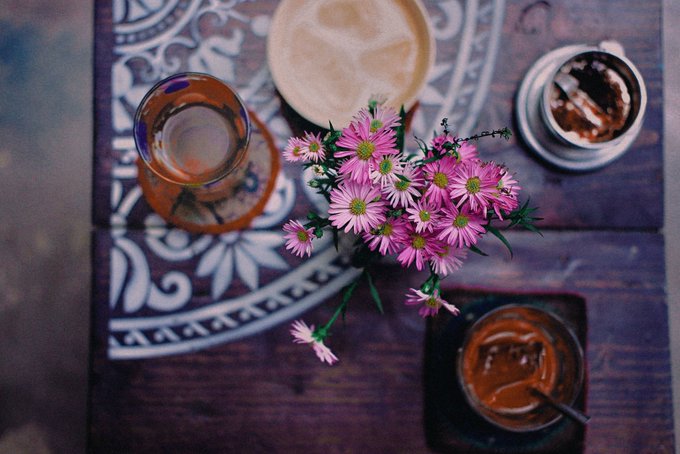The image shows a wooden table with various items placed on top of it, including a vase filled with pink flowers, two cups, and a bowl. The table also has a decorative pattern that adds visual interest to the scene. The caption above the image suggests that there are two biggest threats to one's Web3 portfolio right now: manually managing everything (like the cup) and being slow, inefficient (like the vase with pink flowers). The post mentions that ARC Intelligence sees what's coming and offers a solution in the form of an agent.
