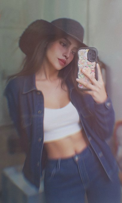 The image features a woman wearing a hat, blue jeans, and a white top taking a selfie with her phone. The photo has been edited or filtered, giving it a vintage appearance. The caption of the image reads "Good morning lovelies Artist" which suggests that this is an artistic creation by someone named Lovelies.