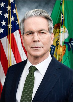 An official portrait of Scott Bessent, the U.S. Treasury Secretary, shown in a dark suit and green tie standing before the American flag and the Treasury Department flag. The image accompanies a post urging passage of the CLARITY Act, quoting Bessent's statement that legislation is "at the 1-yard line" in the Senate.