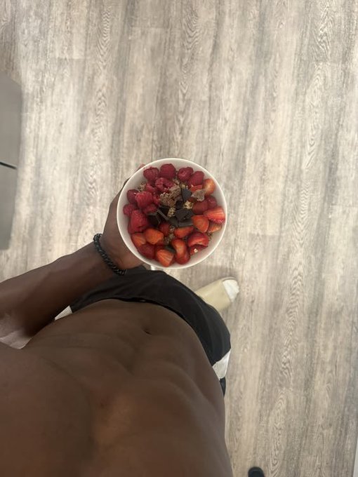 Shirtless man holding a bowl of strawberries, raspberries, granola, and chocolate from above, with his abs and the wood floor visible — a healthy nighttime snack before logging off, fitting the "Gnight fam" vibe of the post tagging @River4fun, @RiverdotInc, and $RIVER.