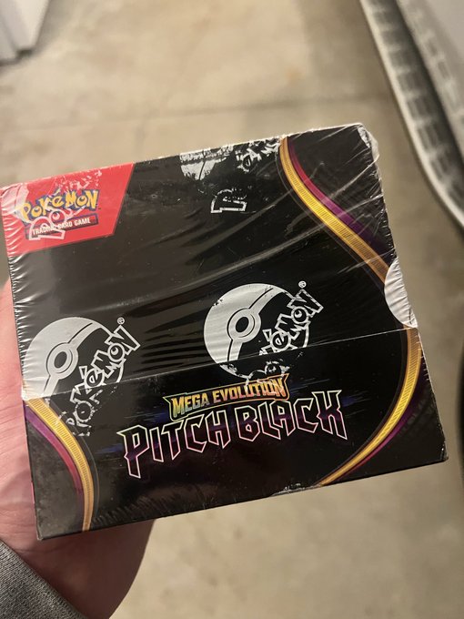 A hand holds a sealed Pokémon Trading Card Game 'MEGA EVOLUTION PITCH BLACK' booster box in its black wrapper.