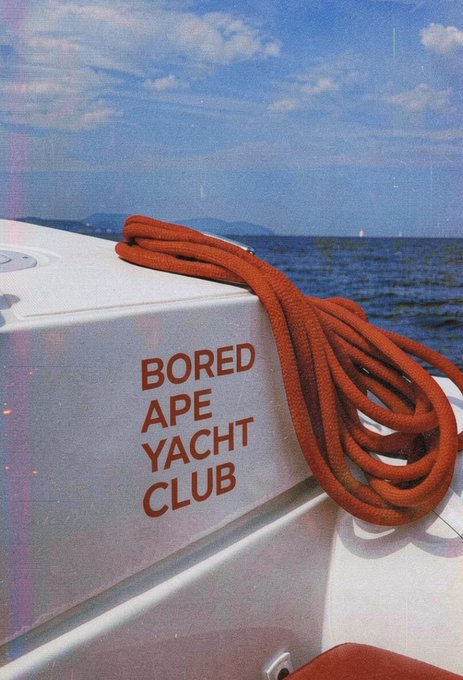 A close-up of orange rope coiled on a white boat with red text reading 'BORED APE YACHT CLUB' printed on its side.