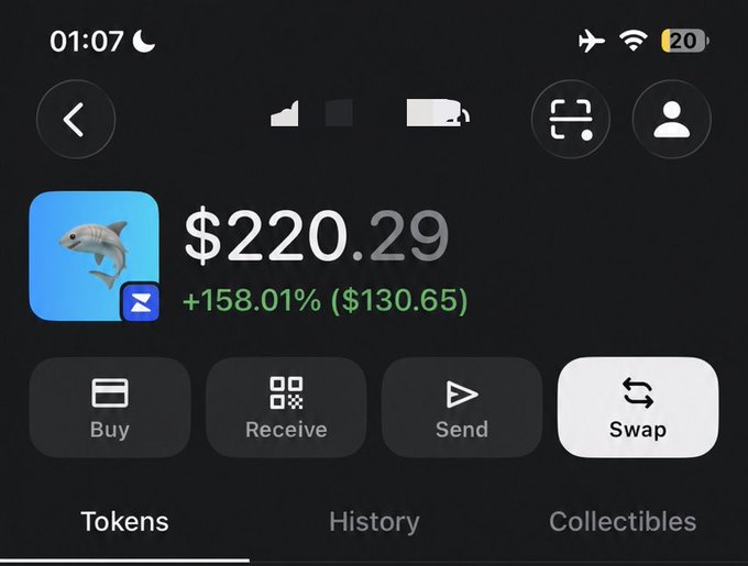 A mobile phone screenshot of a cryptocurrency wallet interface displaying a balance of $220.29 with a +158.01% gain ($130.65), featuring buttons for Buy, Receive, Send, and Swap, with a shark token icon visible.